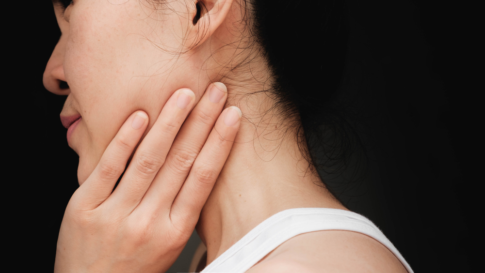girl massaging her chin and neck with tmj pain